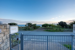 Una entrada con portón a Portela Apartments, con vista al mar y un cielo despejado.