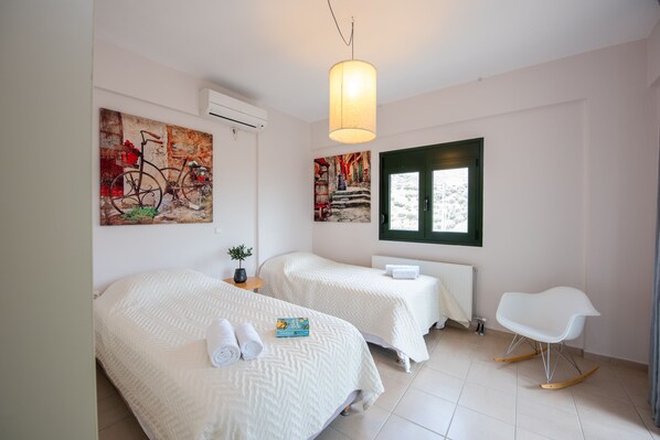 A modern hotel room with two beds, a rocking chair, and artwork on the walls.