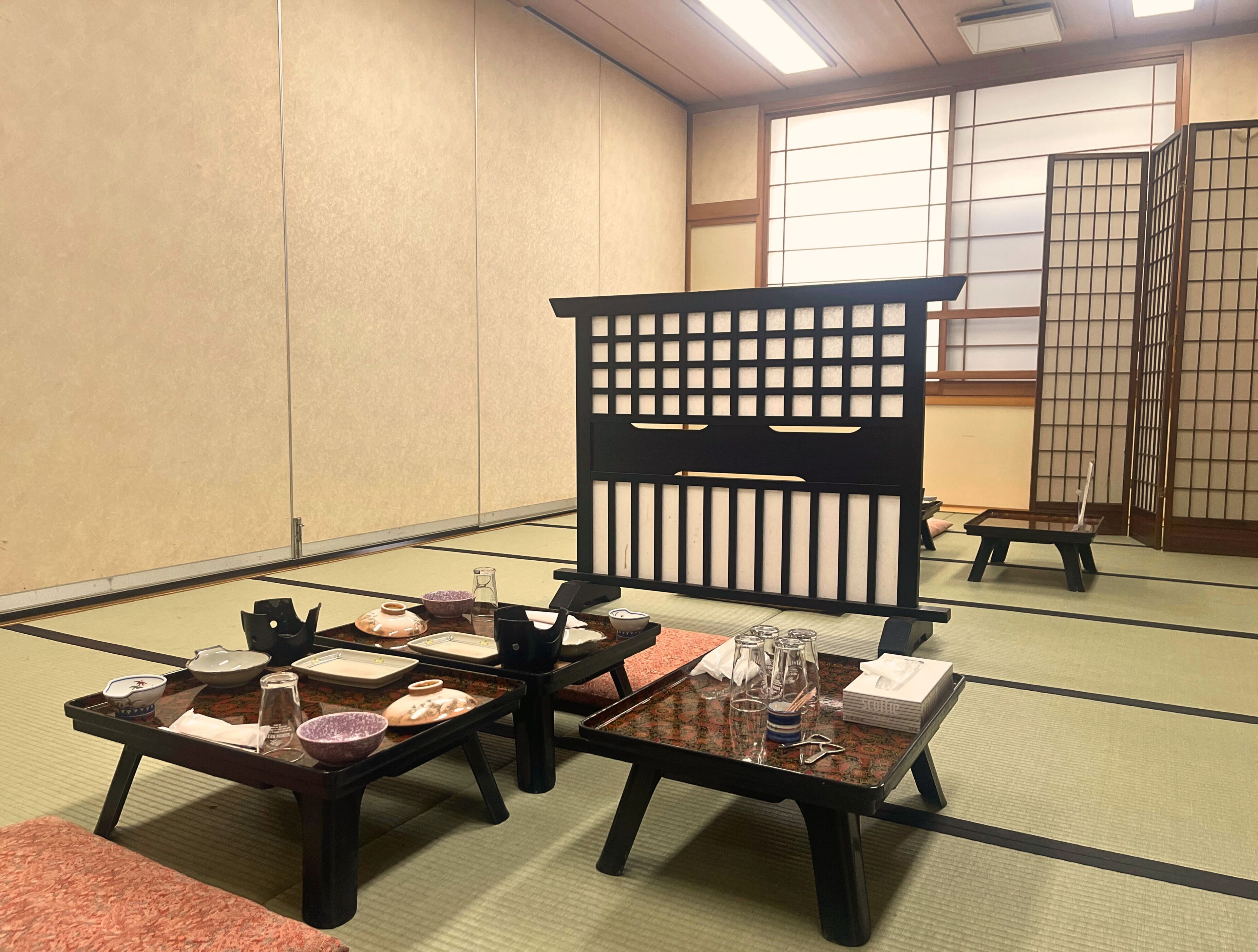 Ein traditioneller japanischer Raum mit Tatami-Boden, niedrigen Tischen und Schiebetüren.