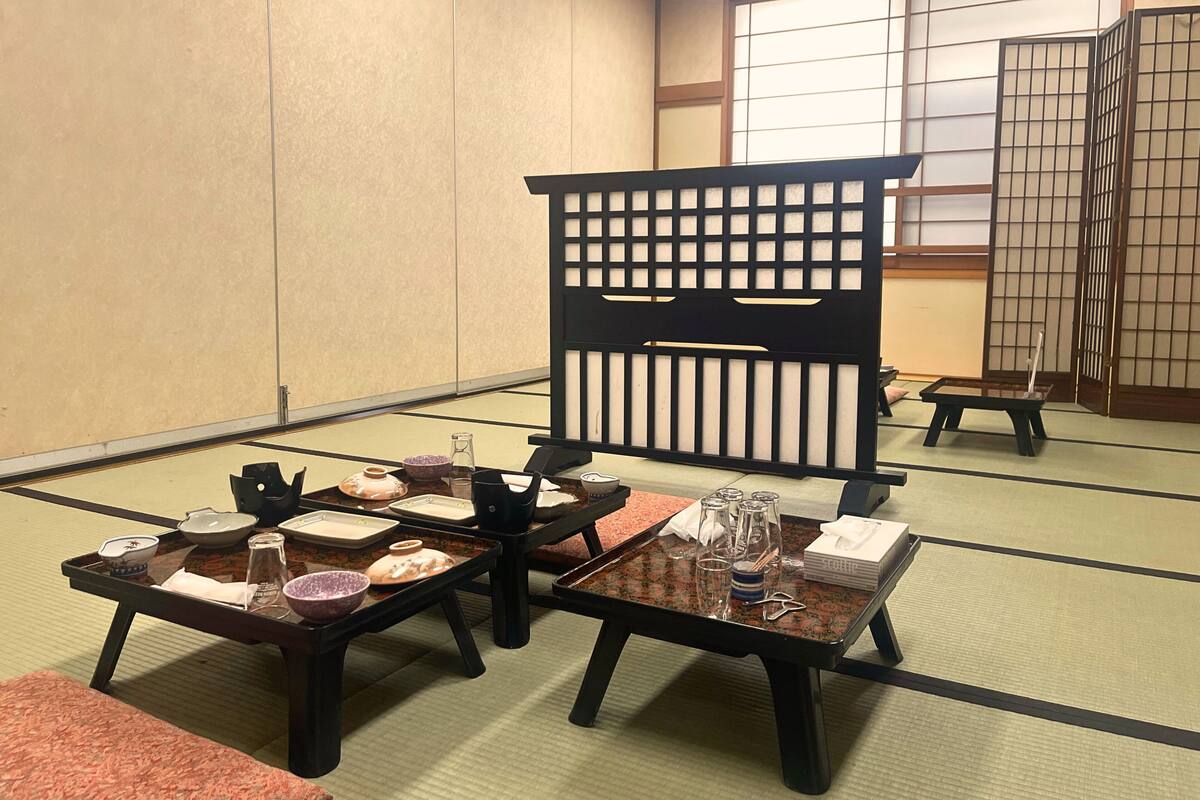 Ein traditioneller japanischer Raum mit Tatami-Boden, niedrigen Tischen und Schiebetüren.