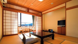 A traditional Japanese room with tatami flooring, a low table, a television, and a view of the outdoors. - Hotel Kinu (Nikko)