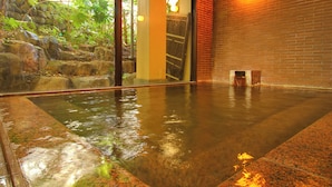 A spacious indoor area with a polished concrete floor, a brick wall, and a glass door leading to an outdoor garden. - Hotel Kinu (Nikko)