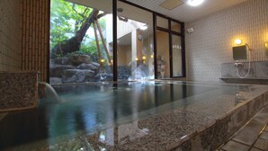 A hot spring bath with a glass barrier, wooden flooring, and a view of a rocky landscape through the glass. - Hotel Kinu (Nikko)