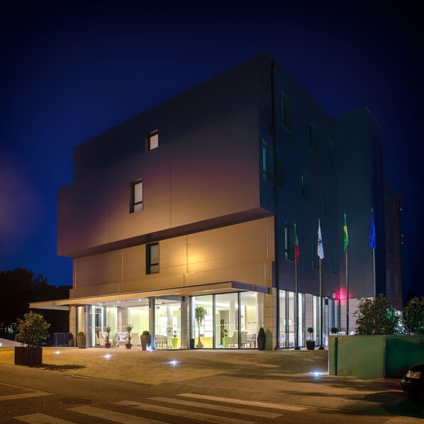 A modern building with a flat roof, large windows, and a well-lit entrance area with outdoor seating. - Lam Hotel Celorico de Basto (Celorico de Basto)