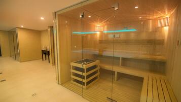Uma sauna com paredes de vidro, bancos de madeira e um banco com suporte para toalhas.