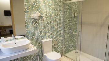 Un baño con lavamanos, inodoro y ducha envuelta en cristal.