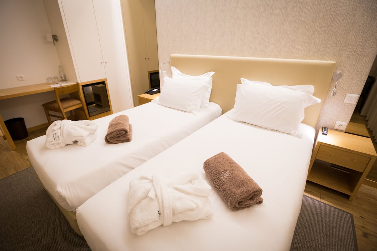 A hotel room with two beds, a desk, and a wardrobe.