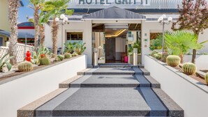 The entrance to Hotel Gritti with a modern facade, steps leading up to the entrance, and a variety of cacti and plants around the building. - Hotel Gritti (Jesolo)