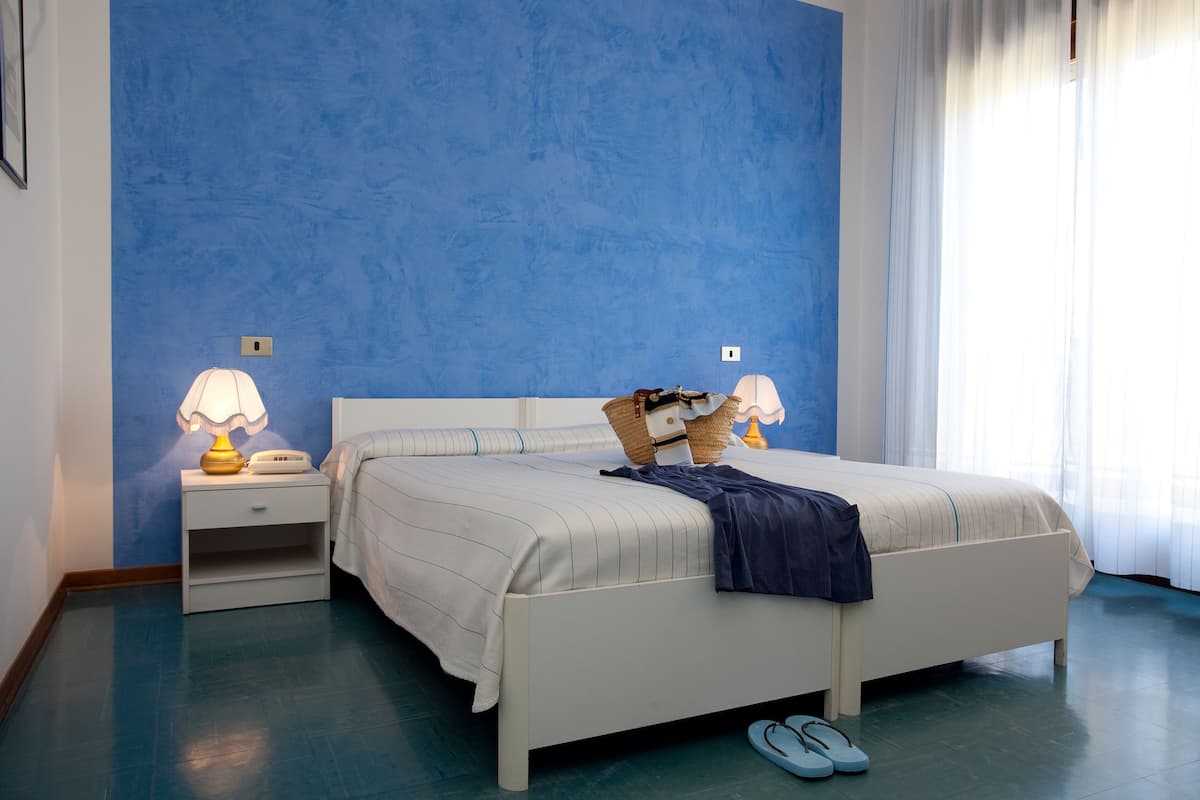 A bedroom with a bed, nightstands, and a window with curtains.