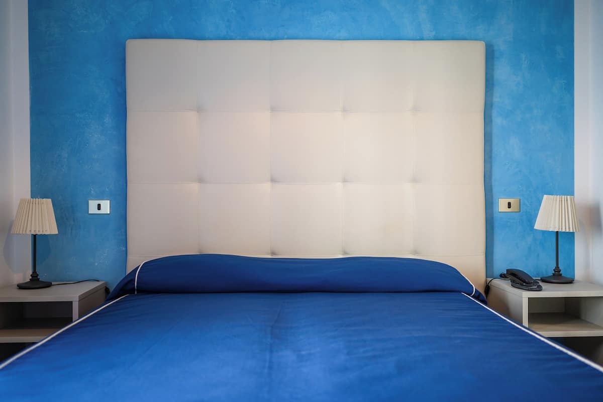 A bedroom with a large bed, two bedside tables, and lamps.