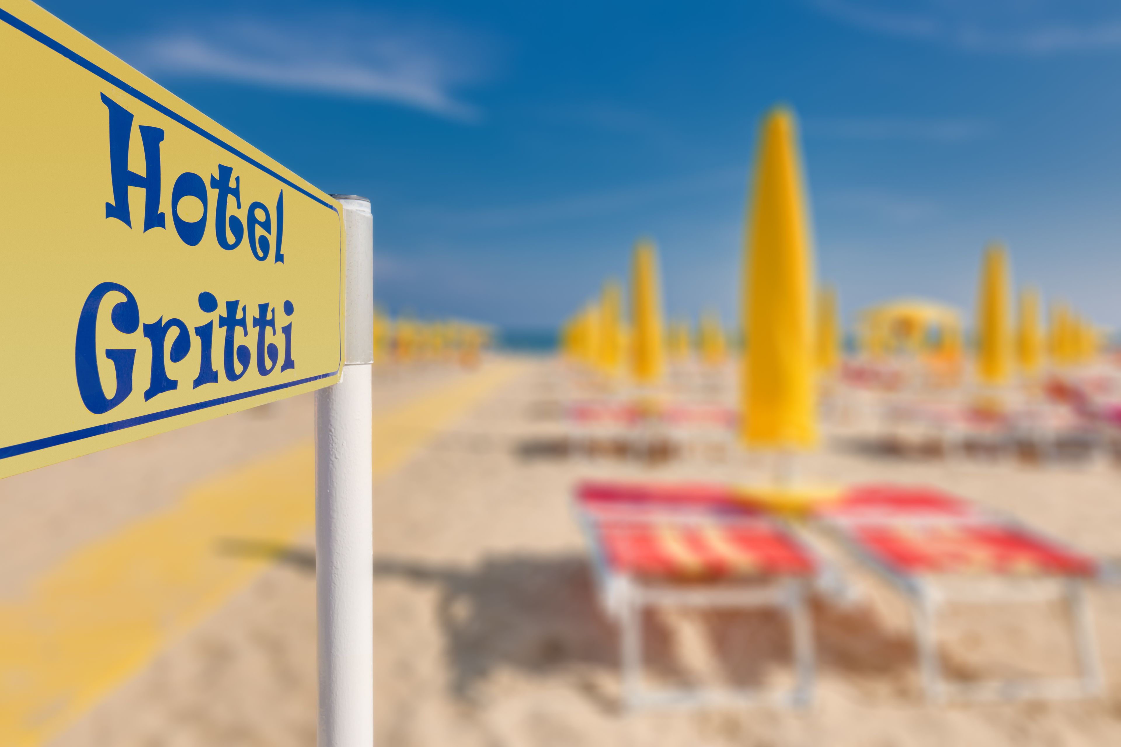 A beachside hotel sign with the name "Hotel Grutti" and rows of beach chairs in the background.