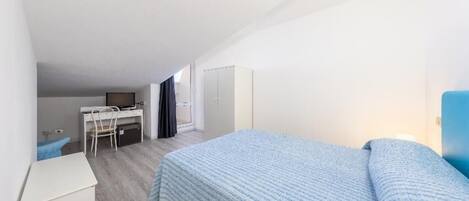 A compact room with a bed, a desk, and a wardrobe.