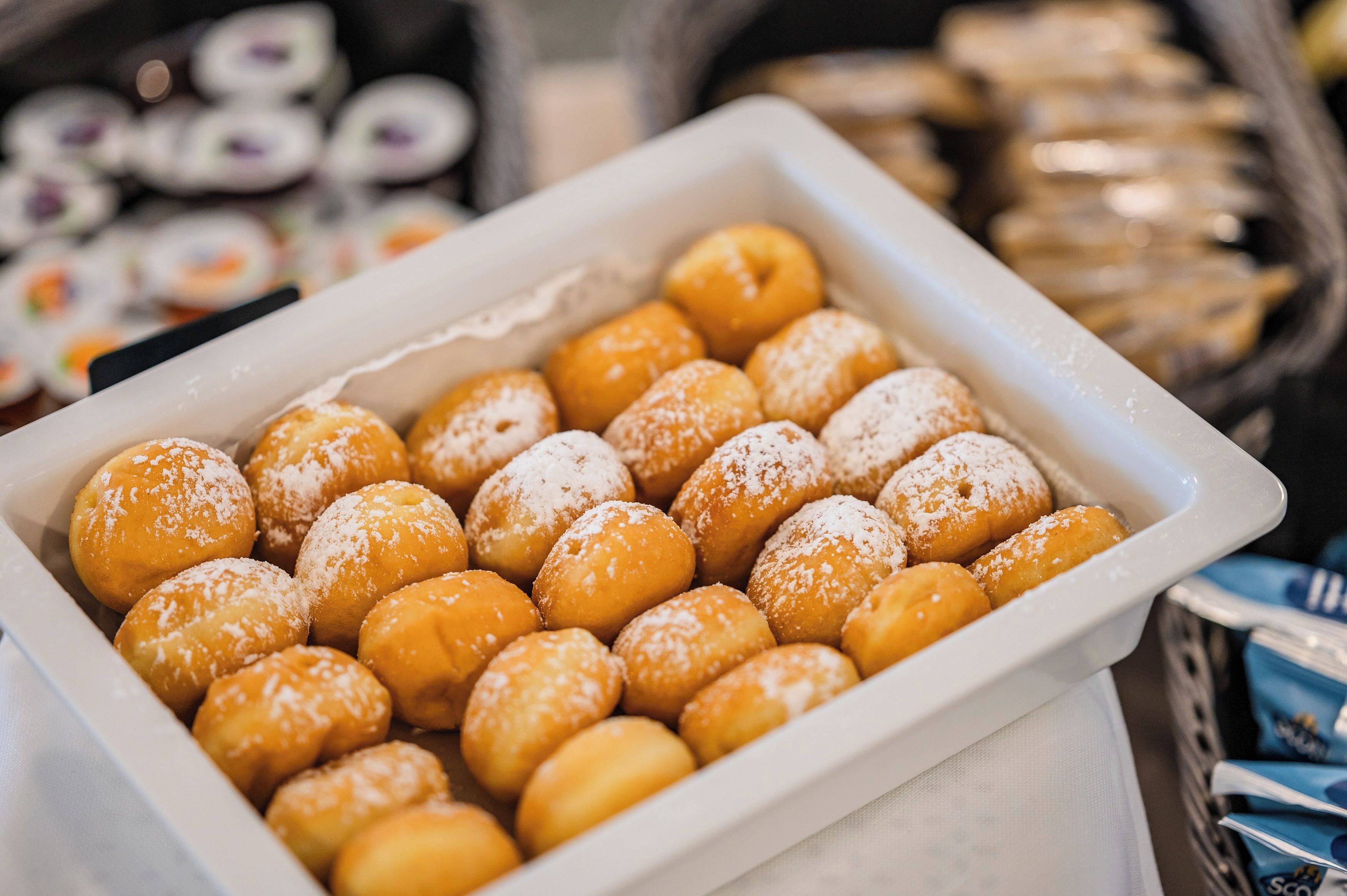 A tray of powdered sugar-covered doughnuts.