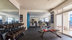 Un gimnàs amb diversos equips, incloent-hi peses, una màquina de premsa i aparells de musculació.