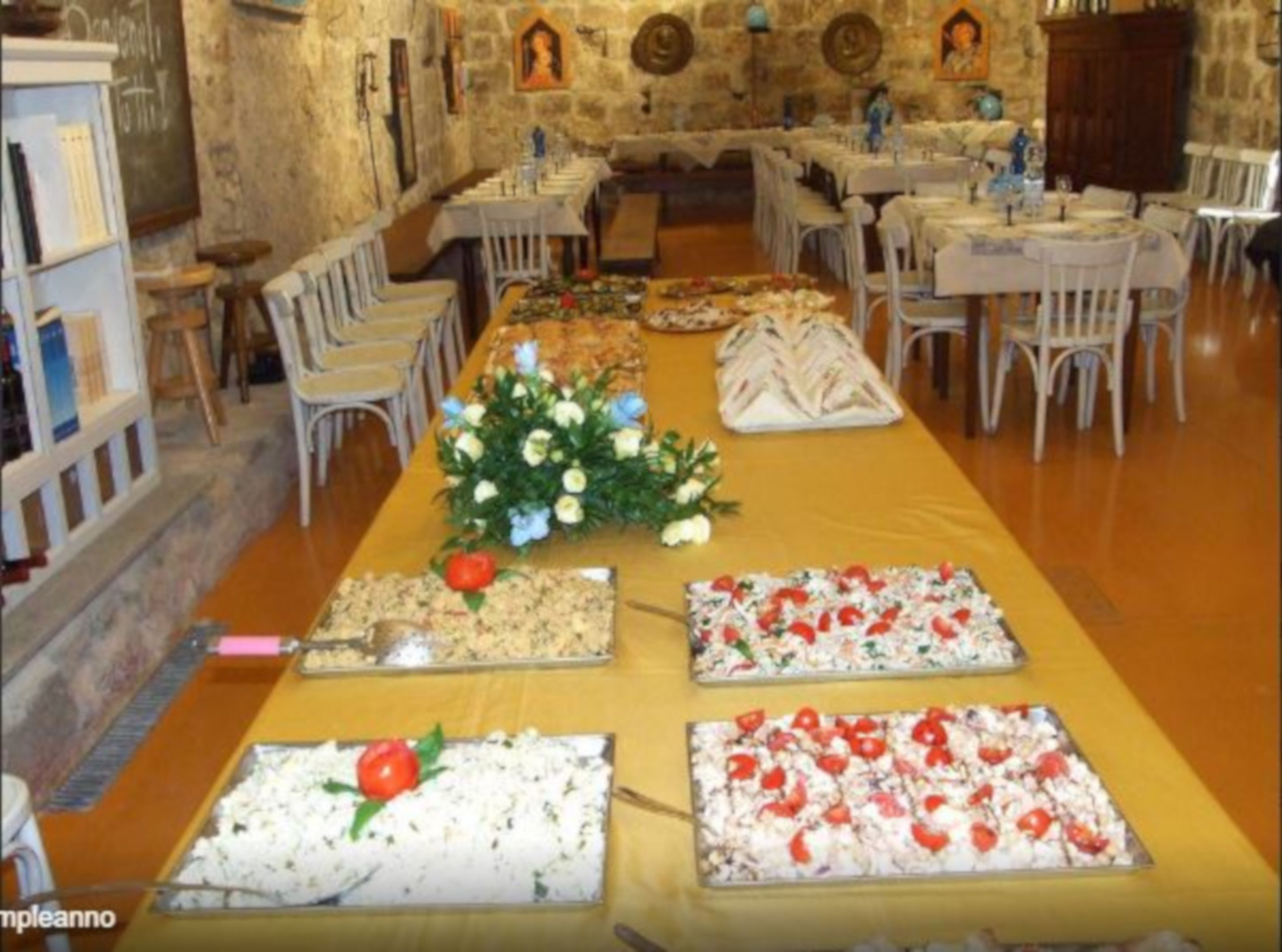 A long table with food displays and a floral centerpiece.