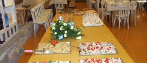 A long table with food displays and a floral centerpiece.