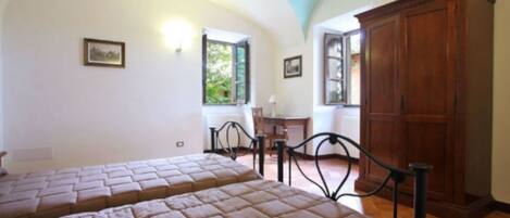 Un dormitorio con dos camas, un armario de madera y un escritorio con una silla.