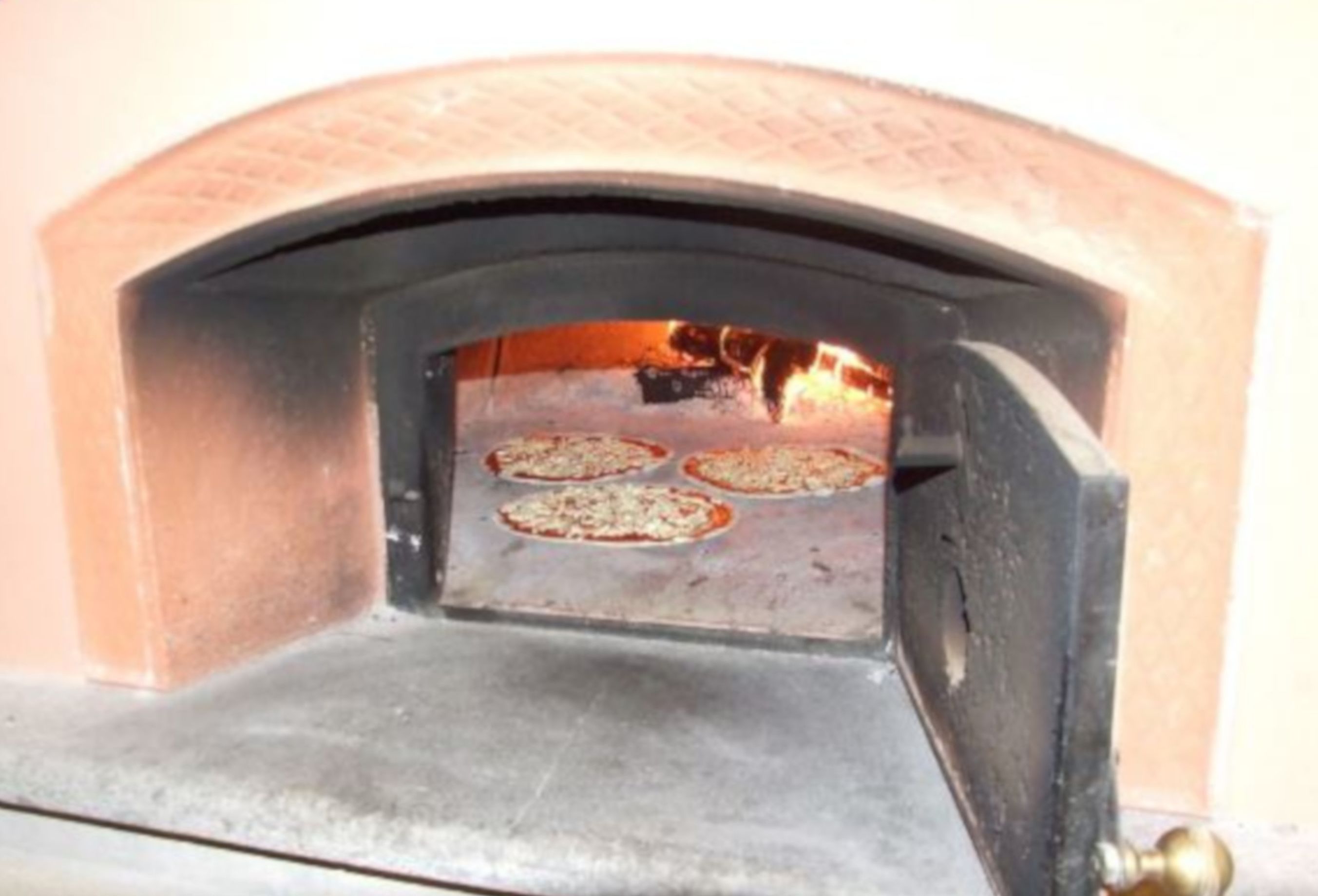 Forno de tijolos com quatro pizzas assando.