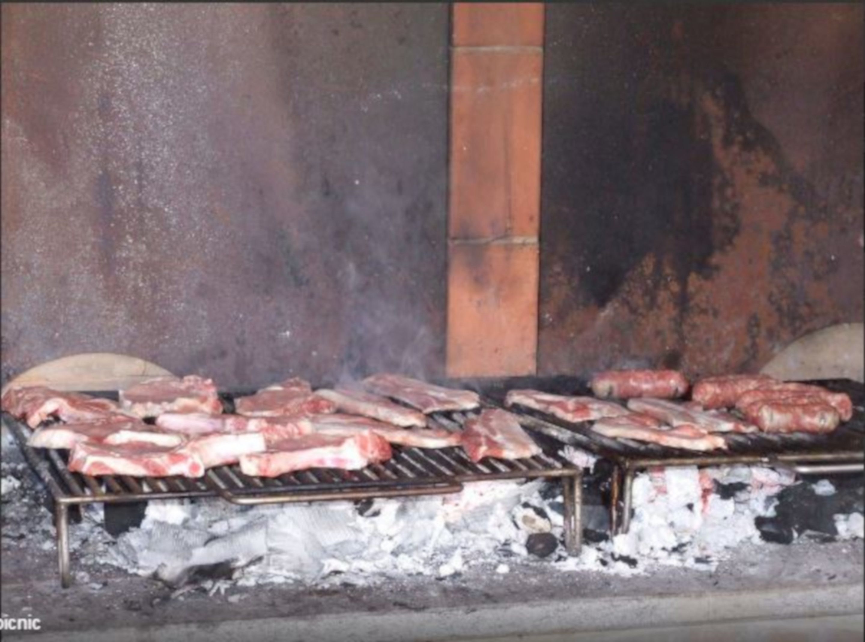 A grill with various meats being cooked.