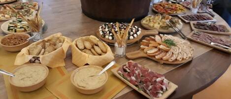 A buffet table with various food items including bread, dips, and meats.