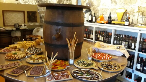 A food and wine tasting area with various dishes and a large barrel in the center. - Antico Borgo La Commenda (Montefiascone)