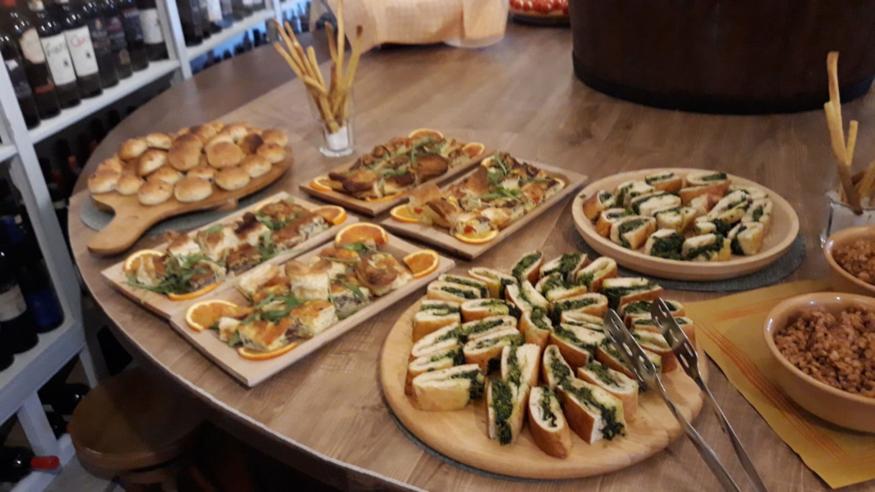 A variety of appetizers on wooden boards, including bread rolls, sandwiches, and vegetable slices, arranged on a wooden table.