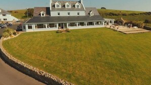 A large, light-colored building with a symmetrical roof and multiple windows, surrounded by a well-maintained lawn and a stone wall. - Castle Murray House Boutique B&B (Dunkineely)
