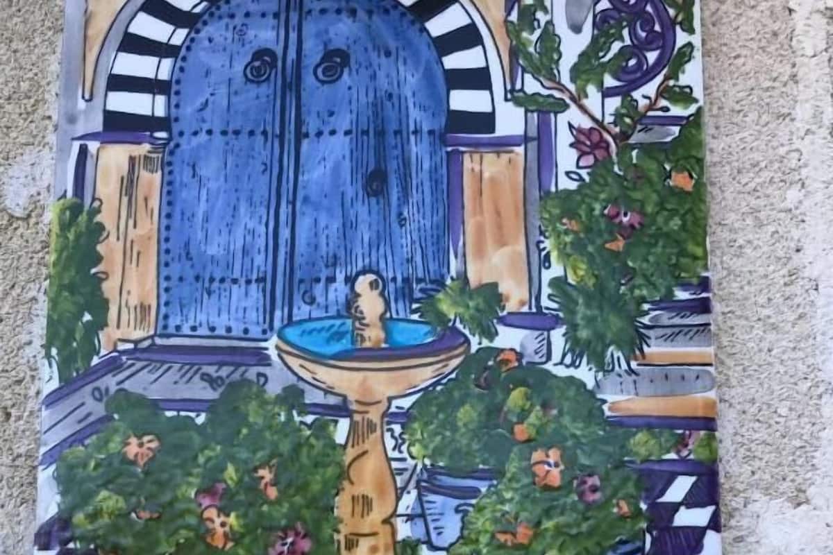 Un cartel con el número '4 Fontana' y una pintura colorida de un edificio con una fuente y plantas en macetas.