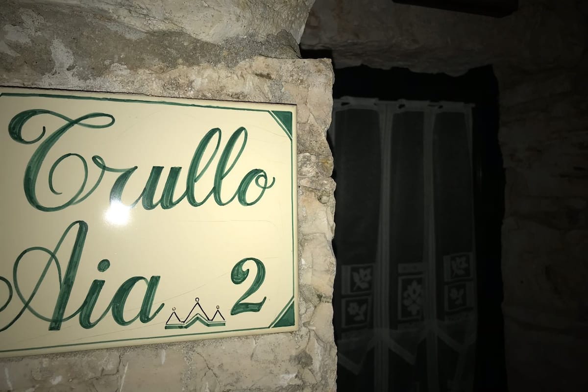 Un letrero con el texto "Trullo Aia 2" en una pared de piedra.