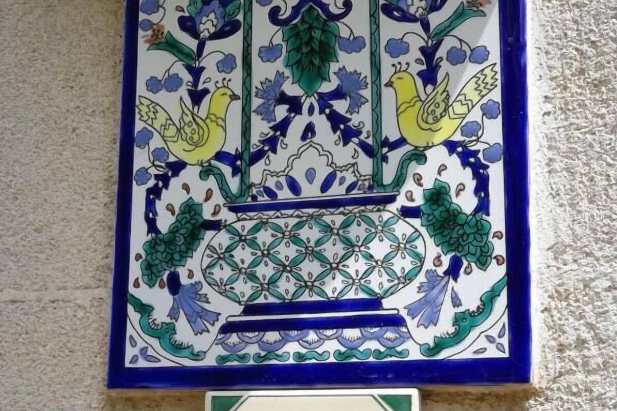 Un letrero en la pared con un diseño de azulejos decorativos y una placa numerada debajo.