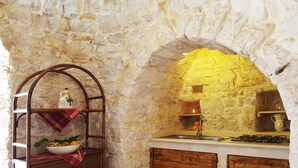Eine rustikale Küche mit Steinwand, Holzschrank und Gasherd.
