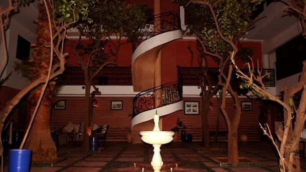 Escadaria em espiral num pátio com uma fonte e árvores.