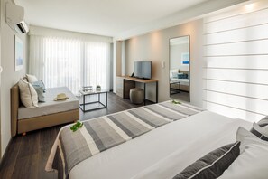 Une chambre d’hôtel moderne équipée d’un grand lit, d’un canapé, d’un petit bureau et d’une télévision.