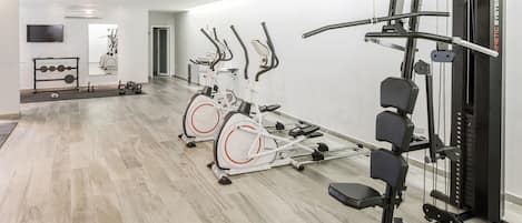 Un gimnàs modern amb bicicletes estàtiques, una pica de musculació i una màquina de cable.