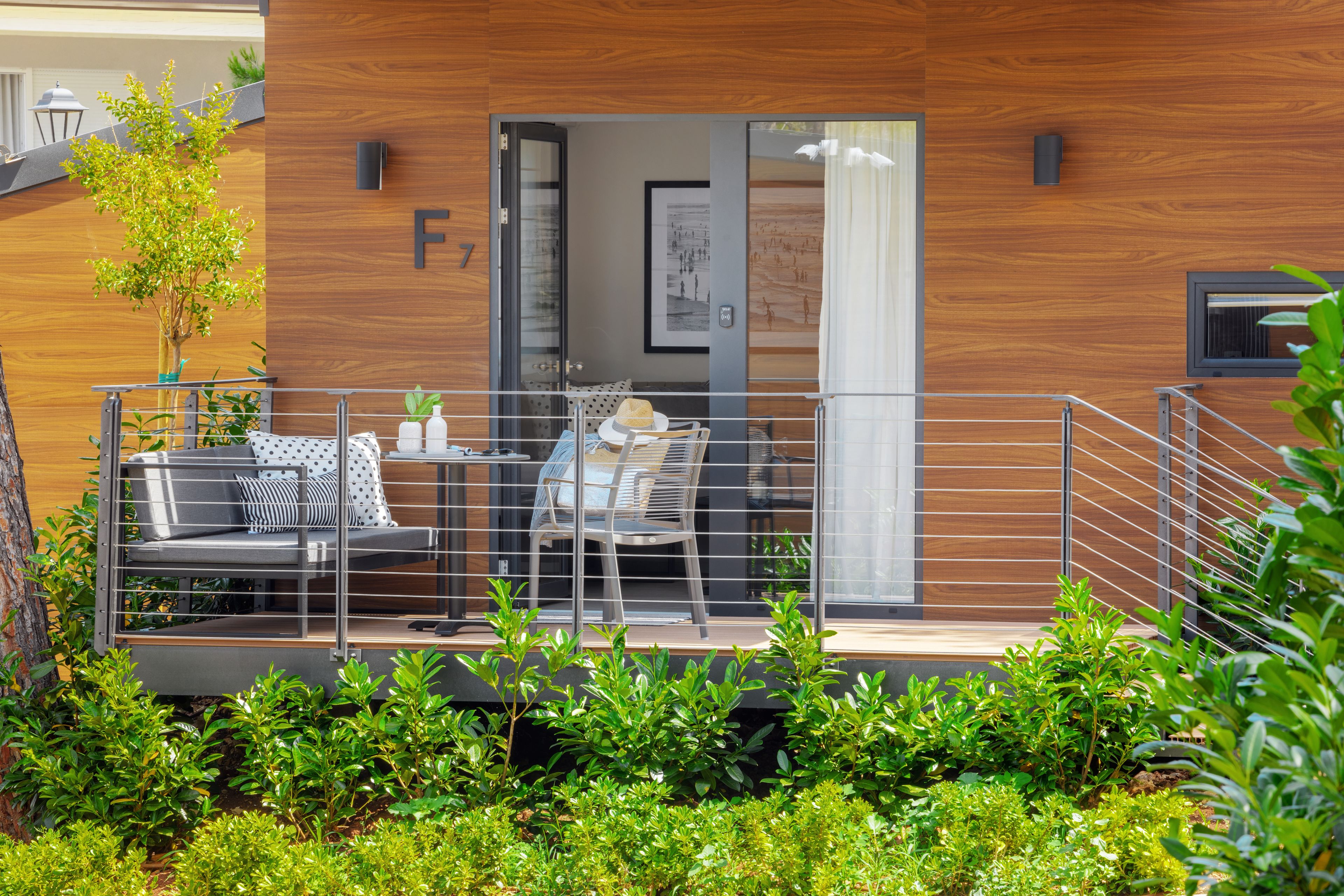 A modern outdoor seating area with a sofa and chairs, a small table, and a potted plant.