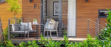 A modern outdoor seating area with a sofa and chairs, a small table, and a potted plant.