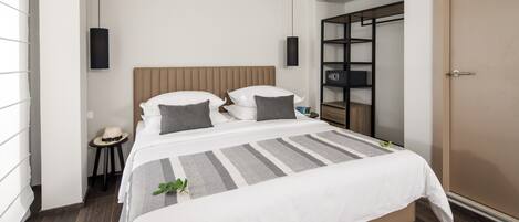 Ein modernes Hotelzimmer mit einem großen Bett, einem Nachttisch, einem Kleiderschrank und einer Hängeleuchte.