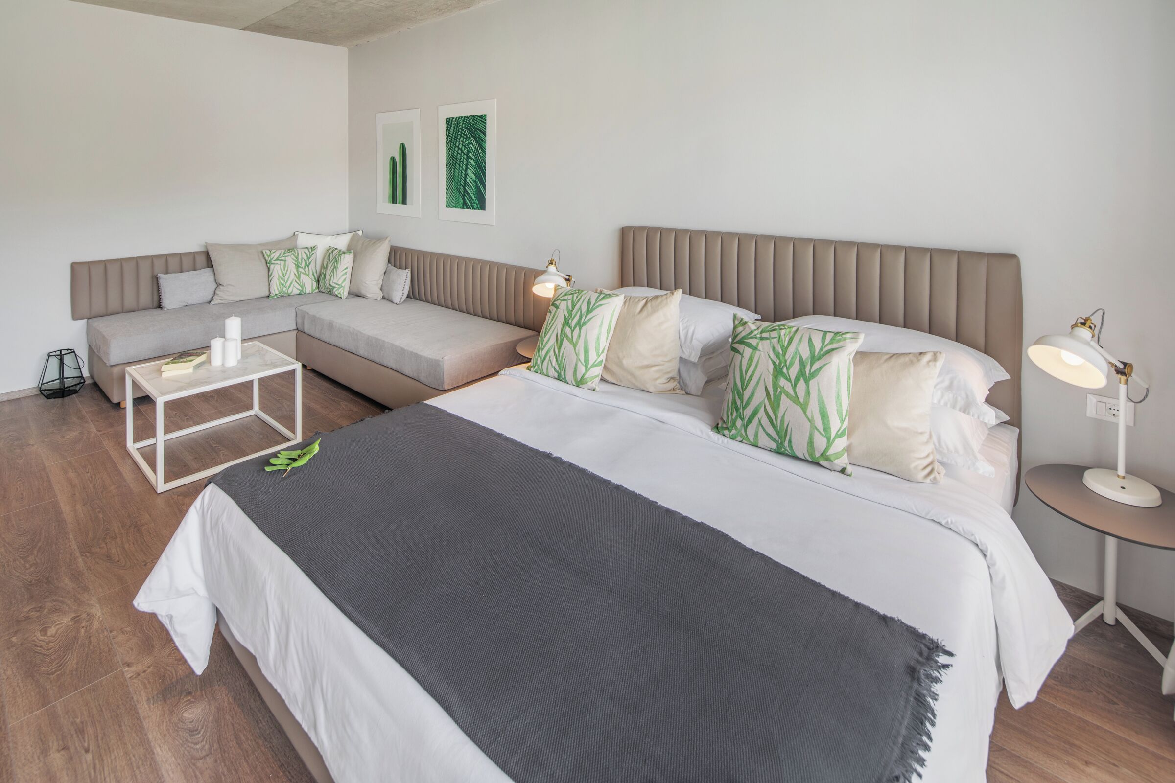 A hotel room with a bed, a sofa, a small table, and a lamp.