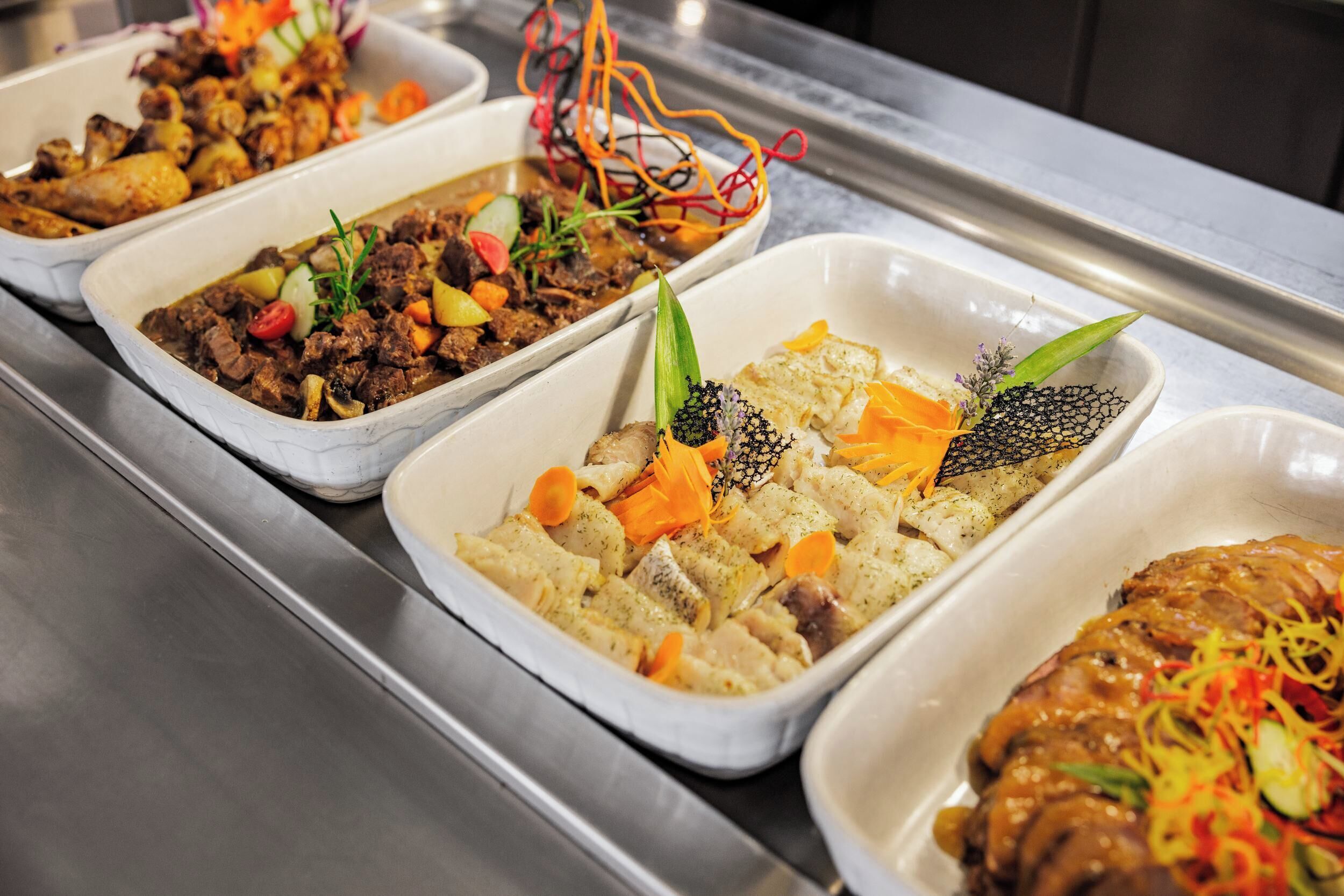Un bufé con diversos platos que incluyen carne, verduras y guarniciones.