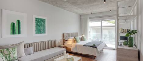 A modern bedroom with a sofa, two beds, a bedside table, and a large window.