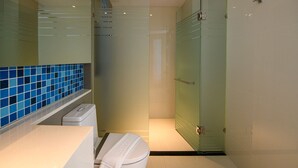 A modern bathroom with a glass shower enclosure, a white toilet, and a blue-tiled sink area. - Deep Blue Z10 Pattaya (Pattaya)