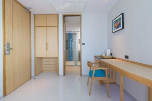 A modern room with a wooden wardrobe, a desk with a chair, and a framed picture on the wall.