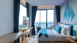 A modern hotel room with a large bed, a desk, and a view of the sea. - Deep Blue Z10 Pattaya (Pattaya)