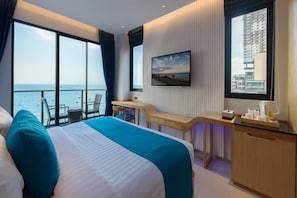 Hotelkamer met een groot bed, een bureau, een stoel, een televisie en uitzicht op zee.