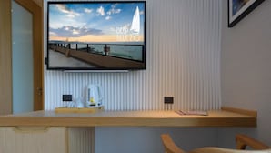 A modern room with a wooden desk, a mounted TV displaying a scenic view, and a wooden chair. - Deep Blue Z10 Pattaya (Pattaya)