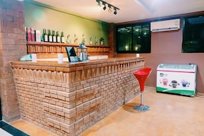 A bar area with a brick counter, a red bar stool, and a beverage dispenser. - Borai Resort Trat (Bo Rai)