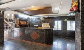 A reception desk with a sign reading "Vijaya Residency." There are prayer wheels and a statue above the desk. - Itsy Hotels Vijaya Residency (Udupi)
