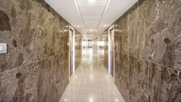 A modern hallway with marble walls and a shiny tiled floor, leading to an elevator. - Itsy Hotels Vijaya Residency (Udupi)