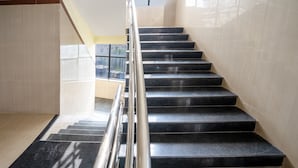 A staircase with black steps and a metal handrail, leading to a higher floor. - Itsy Hotels Vijaya Residency (Udupi)