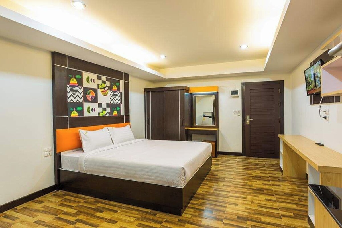 A modern bedroom with a large bed, a wardrobe, a mirror, and a TV.